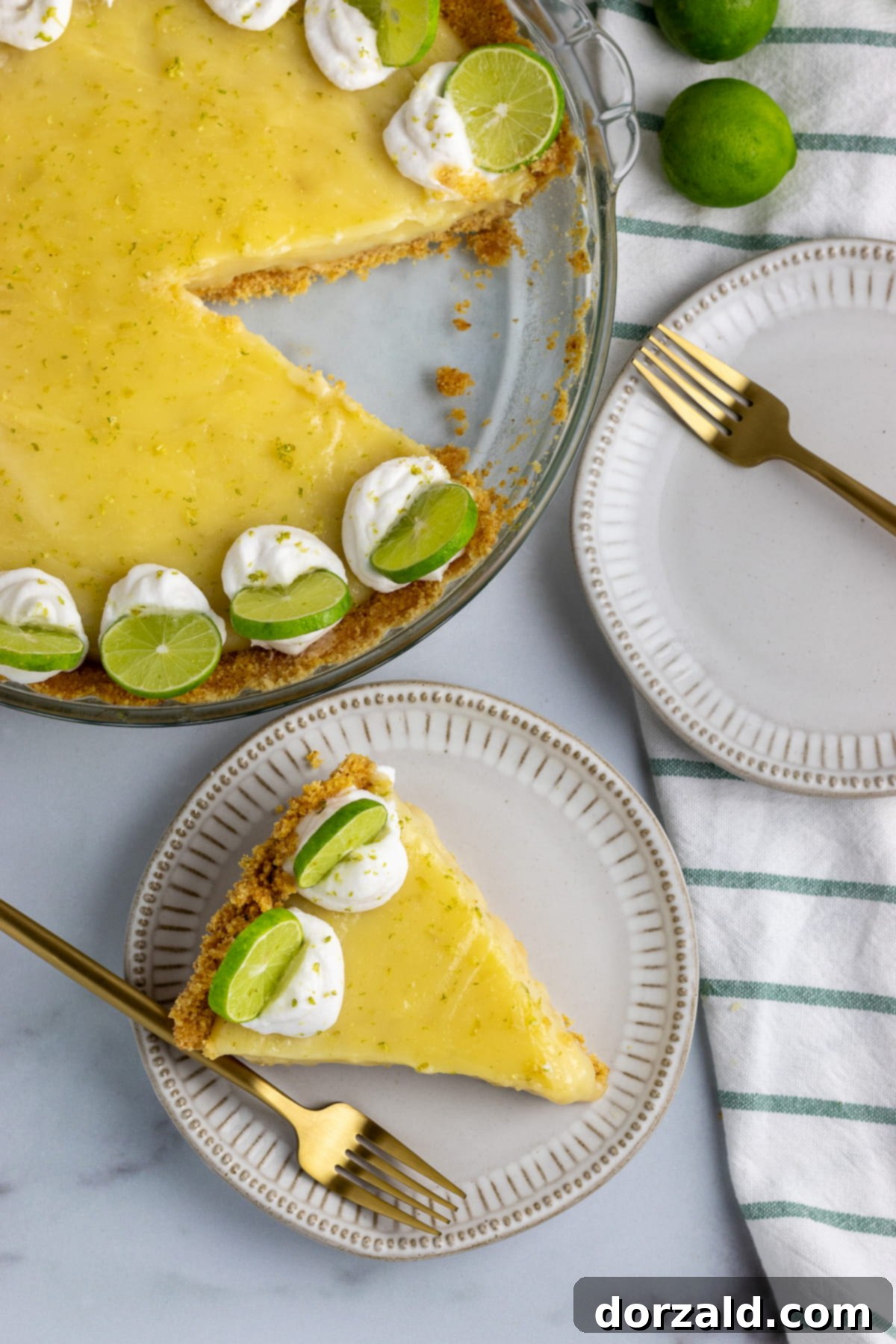 A slice of creamy gluten-free dairy-free key lime pie topped with whipped cream and a lime slice on a white plate.