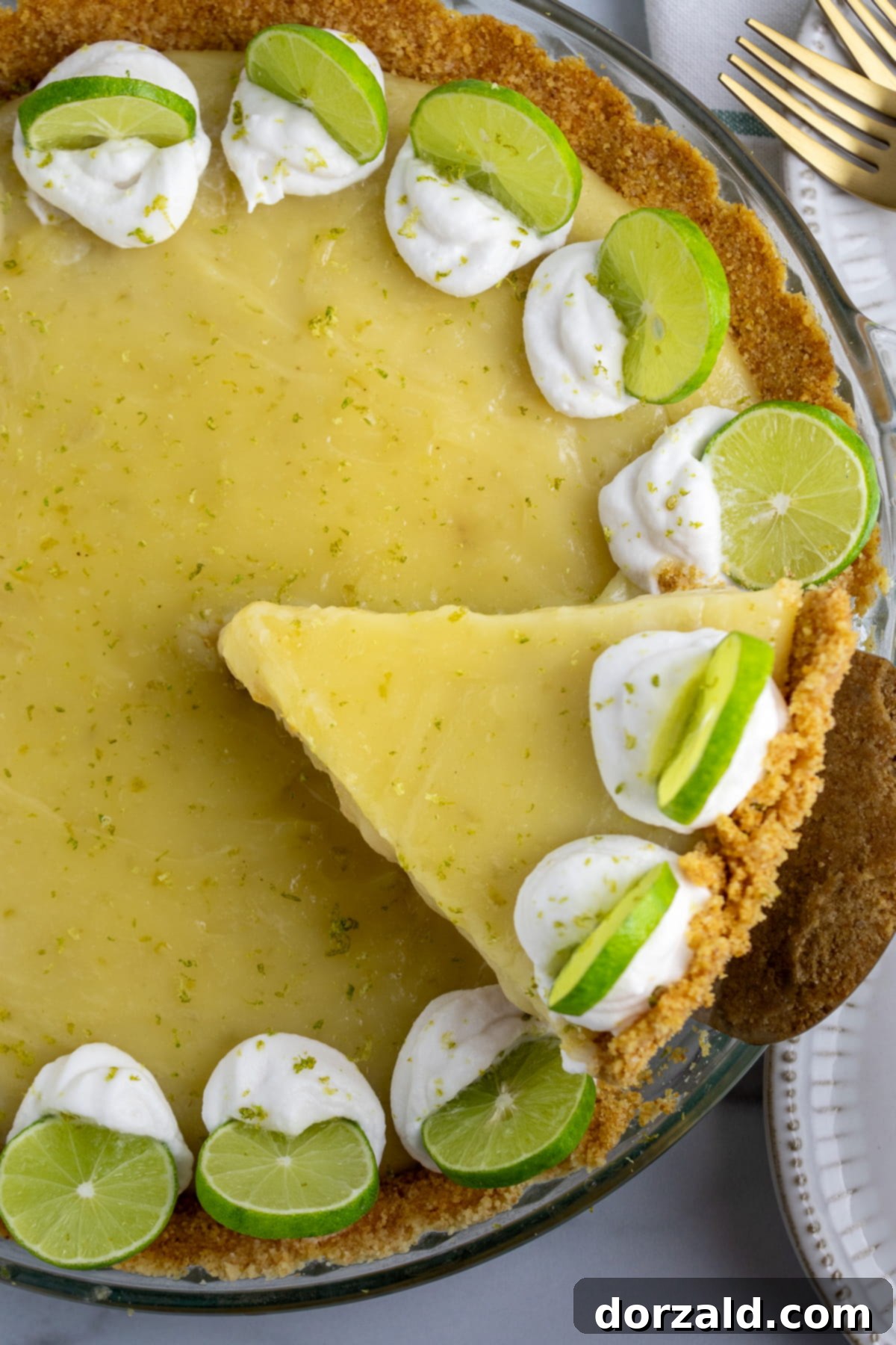 A vibrant gluten-free dairy-free key lime pie, garnished with fresh lime slices and zest, ready to be served.
