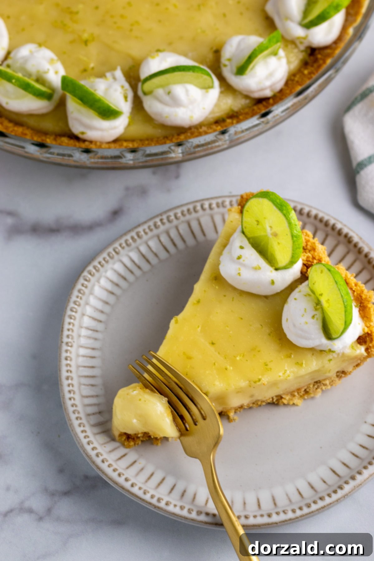 A slice of gluten-free dairy-free key lime pie topped with homemade whipped cream and lime zest.
