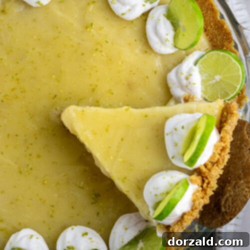 A slice of creamy gluten-free dairy-free key lime pie with whipped cream and lime zest.