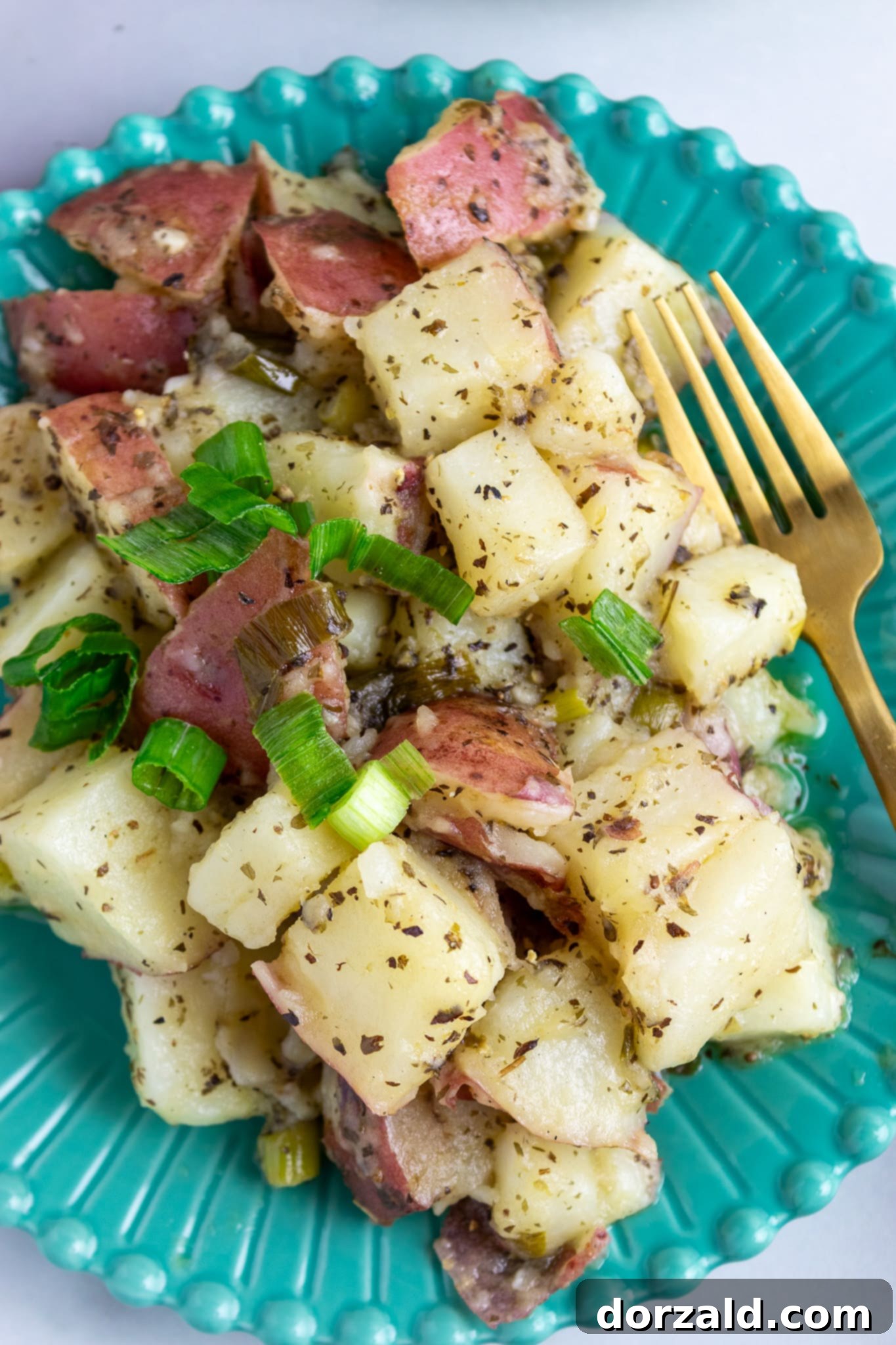 A large cast iron skillet filled with Zoe's Kitchen copycat potato salad being grilled to achieve crispy edges.