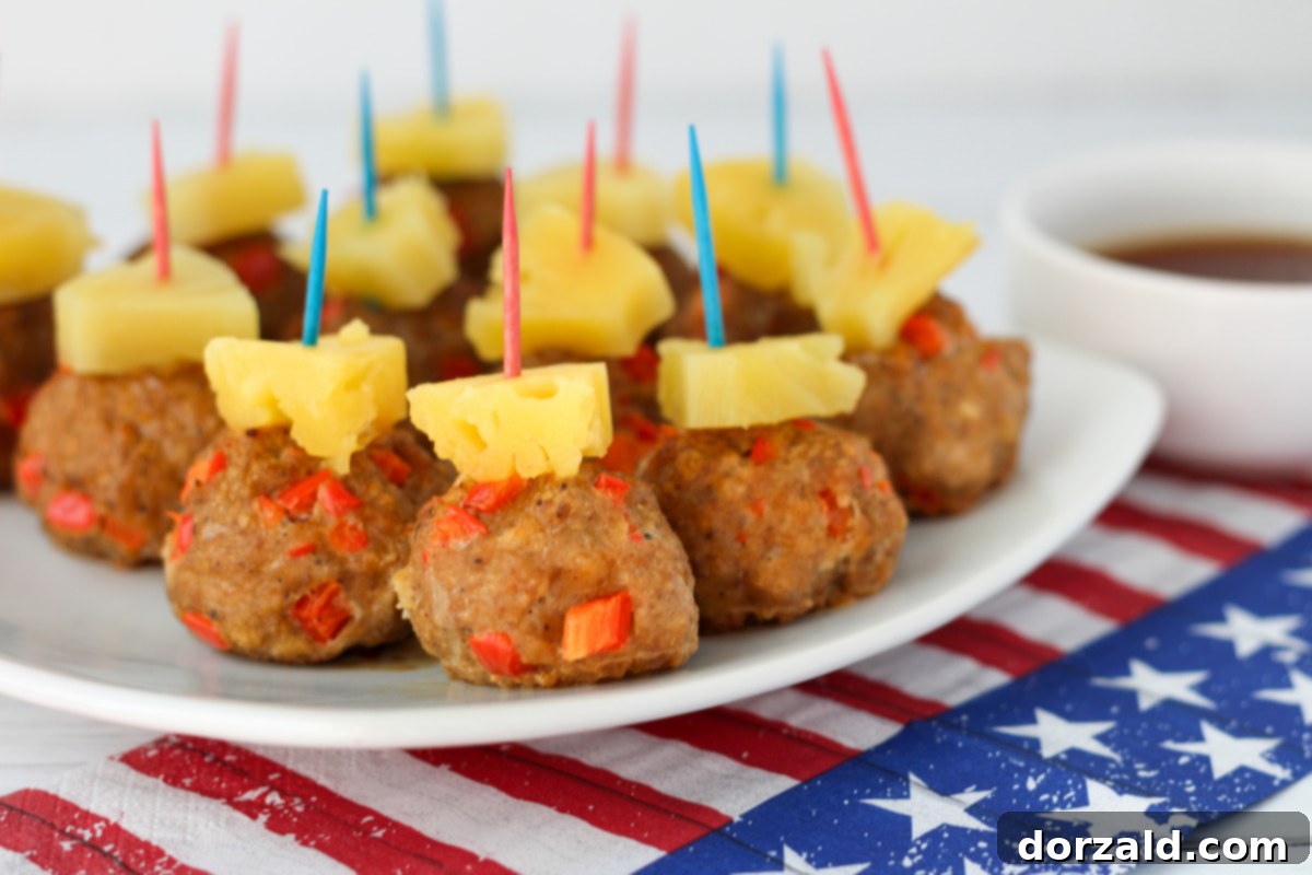 A close-up shot of Spicy Hawaiian Turkey Meatballs topped with pineapple chunks and toothpicks, arranged on a serving platter.