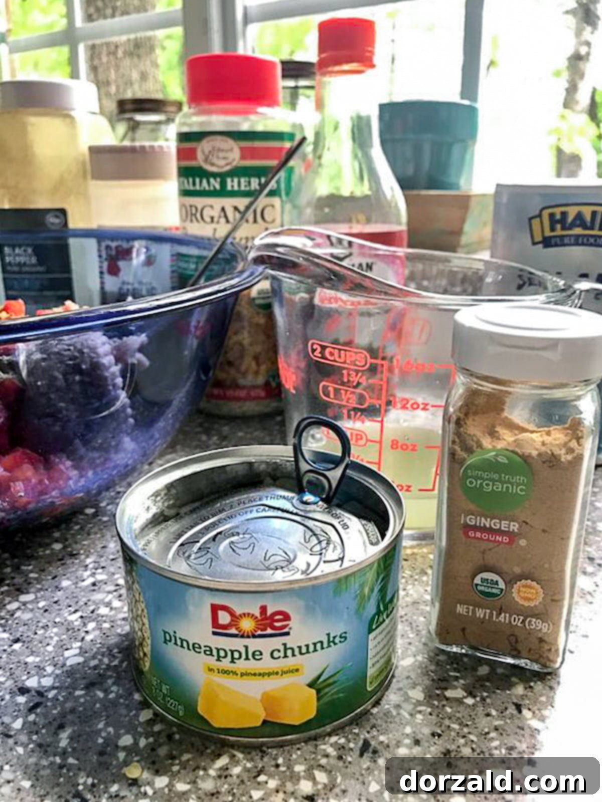 A flat lay of fresh ingredients including ground turkey, red bell pepper, pineapple chunks, teriyaki sauce, and various spices, ready for making meatballs.
