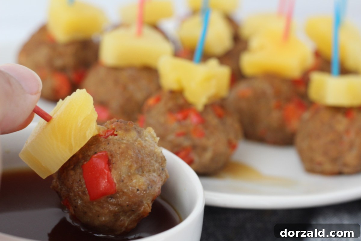 A beautifully arranged platter of Spicy Hawaiian Turkey Meatballs, each topped with a pineapple chunk and a toothpick, ready to be served.